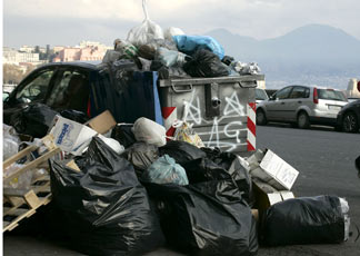 Un cumulo di rifiuti accatastati accanto a un'auto per le vie di Napoli