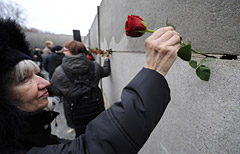 Una dona posa una rosa rossa su un segmento del muro di Berlino (Afp Photo/John MacDougall)