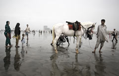 A Clifton Beach, spiaggia di Karachi, un profugo afghano cerca di guadagnarsi da vivere portando in giro a cavallo i turisti